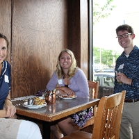 three alumni sitting at a table and smiling for camera